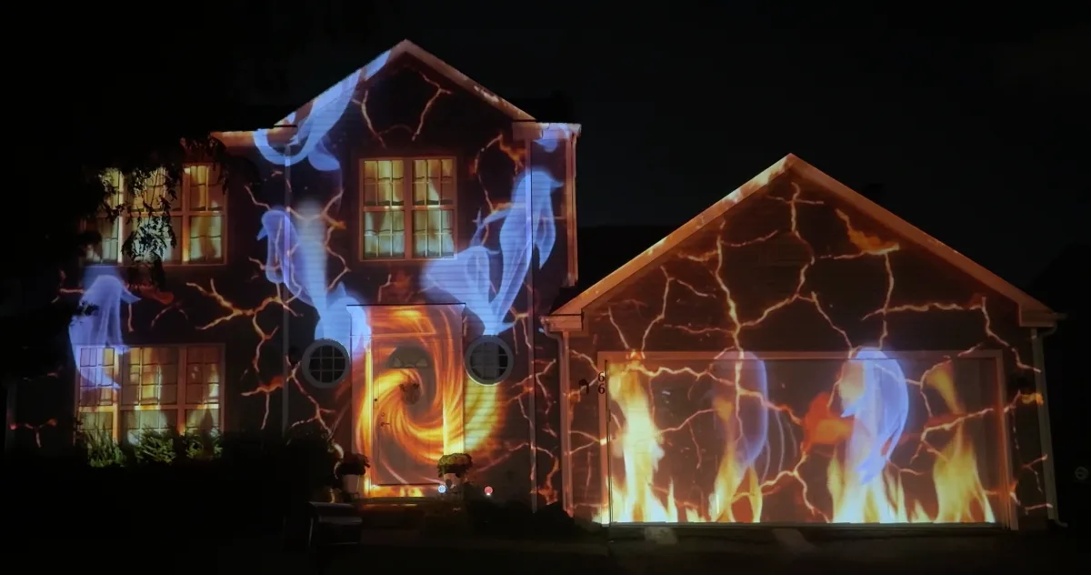 A brick two-storey home mapped with a gateway to the underworld: molten orange cracks running across the walls, flames over the garage door and ghosts drifting between the lit windows