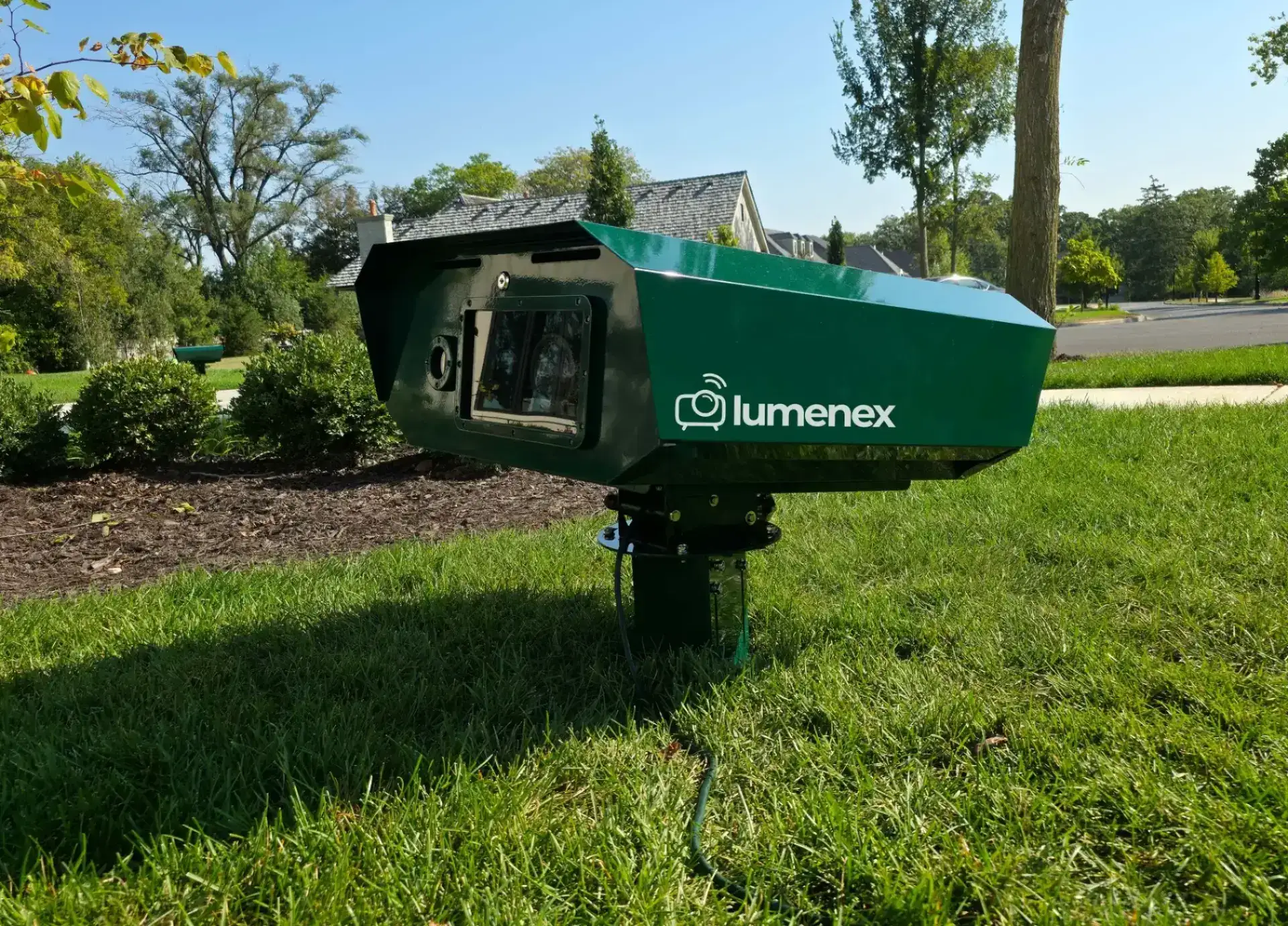The green Illuminator LX60 projector on its mounting pole in a front garden
