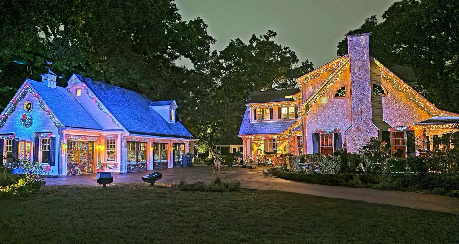 Two LX60 Aura units on a lawn lighting a house and its garage for Christmas